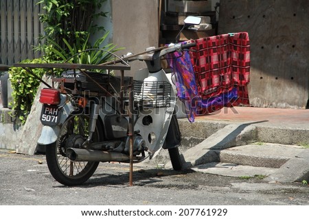 GEORGE TOWN, MALAYSIA - MAY 31: An old motor bike with a sarong draped over the handle bars in a side street of Georgetown, Malaysia on the 31st May, 2014.