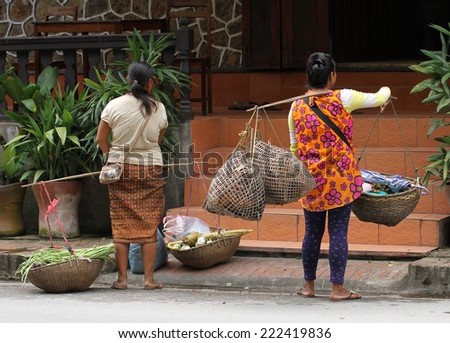 LUANG PRABANG, LAOS - AUGUST 15th: A common sight of a hill tribe women carrying live poultry and fruit in baskets over their shoulders in Luang Prabang, Laos on the 15th August, 2014.