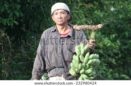 LUANG PRABANG - AUGUST 16: A closeup of a local hill tribe man walking along the road carrying bananas in the countryside near Luang Prabang, Laos on the 16th August, 2014.