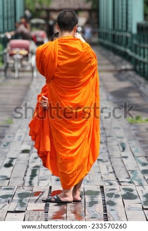 CHIANG MAI, THAILAND - AUGUST 30: Two monks in traditional saffron robes on the iron Memorial Bridge over the Pai River outside of Pai near Chiang Mai, Thailand on the 30th August, 2014.