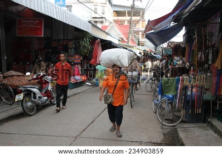 MAE SOT, THAILAND - SEPTEMBER 1:\
A local woman carrying a heavy bag on her head at the fresh food market in Me Sot, Thailand on the 1st September, 2014.
