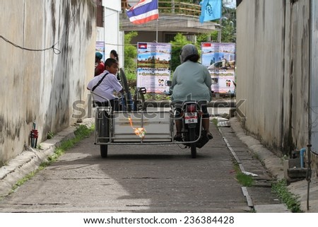 KANCHANABURI, THAILAND - SEPTEMBER 3: People riding motor bikes down an alleyway in the town of Kanchanaburi, Thailand on the 3 September, 2014.