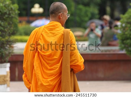 VIENTIANE, LAOS - AUGUST 7: A monk in saffron robes walking the street in the town of Vientiane, Laos on the 7th August, 2014.