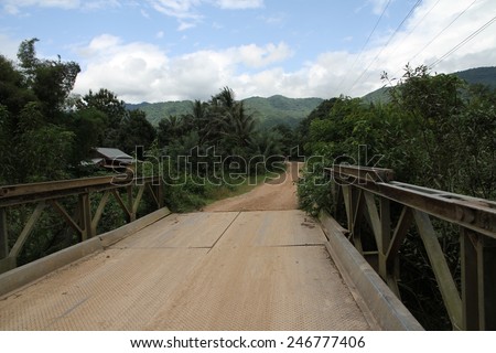 The red earth roadway  over a wooden bridge outside of Vang Vieng, Laos.