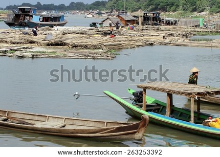 MANDALAY, MYANMAR - NOVEMBER 7:\
Traditional wooden boats with the shanty town on the riverbanks of the Irrawaddy River in the background near the town of Mandalay, Myanmar on the 7th November 2012.