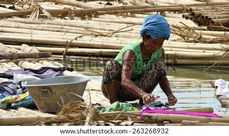 MANDALAY, MYANMAR - NOVEMBER 7:
A woman washing clothes in the shanty town built on bamboo poles on the riverbank of the town of Mandalay, Myanmar on the 7th November 2012.