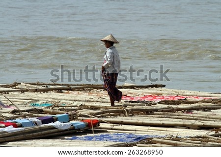 MANDALAY, MYANMAR - NOVEMBER 7:
A villager standing on the bamboo poles of the shanty town on the riverbank of the town of Mandalay, Myanmar on the 7th November 2012.