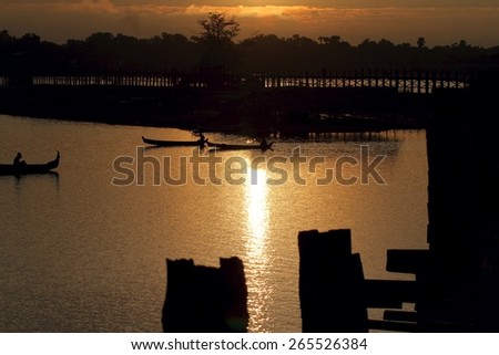 The early morning golden glow seen from the famous U Bein Bridge and reflected on Lake Taungthaman, near Mandalay, Myanmar.