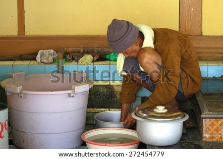 MANDALAY, MYANMAR - NOVEMBER 8: A local Burmese man washing up dishes from one of the many food places at the foot of Sutaungpyei Pagoda on  Mandalay Hill, Mandalay, Myanmar on the 8th November, 2012.