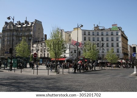 PARIS, FRANCE - APRIL 22nd: People waiting at a bus stop with advertising in the background in the street of the 20th Arrondissement of Paris, France on the 22nd April, 2015.
