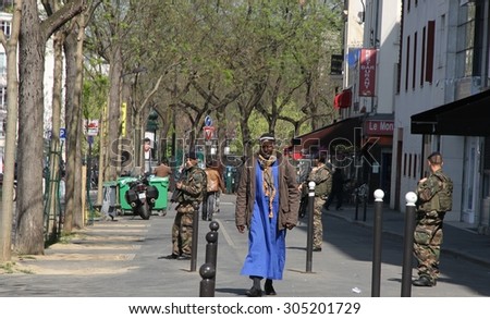 PARIS, FRANCE - APRIL 22nd: A street scape view of a roadway with a tall african-french man and soldiers in the background in the 20th Arrondissement of Paris, France on the 22nd April, 2015.