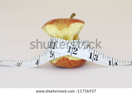 An half eaten apple with a measuring tape around it.