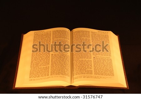 The Holy Bible open under candle light.