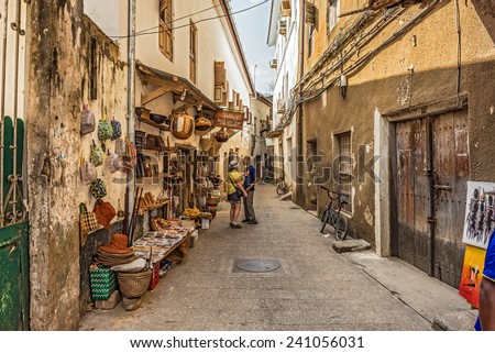STONE TOWN, ZANZIBAR - OCTOBER 24, 2014: Tourists on a typical narrow street in Stone Town. Stone Town is the old part of Zanzibar City, the capital of Zanzibar, Tanzania.