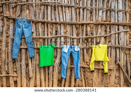 Clothes hanging on a wall of a wooden hut in Africa