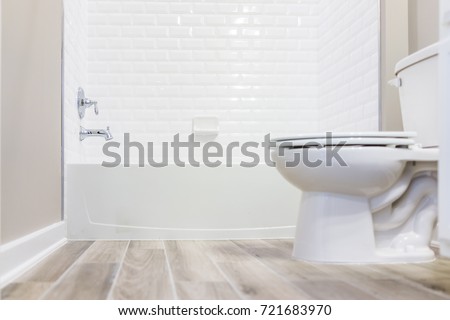 Modern white plain clean toilet bathroom with shower tiles and hardwood floors from ground level