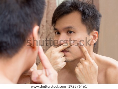 Mirror reflection of a young asian handsome man viewing his face