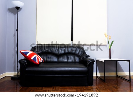 Black Leather Sofa, union jack backrest Pillow, Floor Lamps, Flowers, Vase, White Table on Wood Floor in the grey room