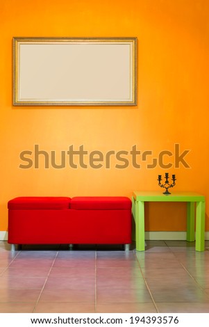 red stool chair, candlestick on green table and picture frame on orange wall