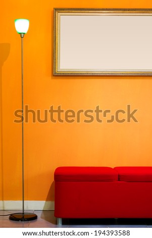 red stool chair, floor lamp and picture frame on orange wall