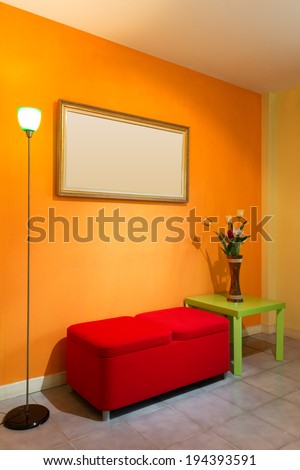 red stool chair, floor lamp, vase on green table and picture frame on orange wall