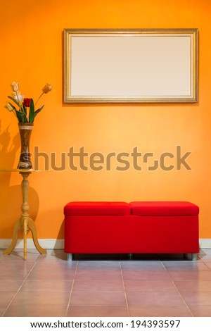 red stool chair, flowers in wood vase and picture frame on orange wall