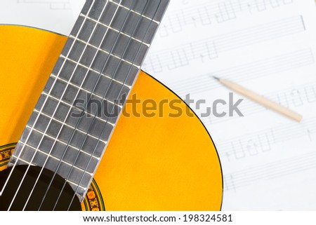 guitar and pencil on music sheet for composer