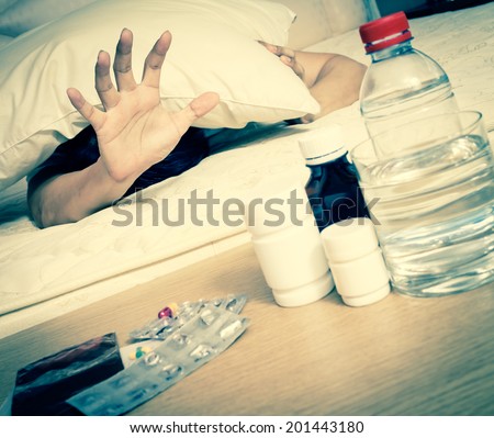 Asian Handsome Man in bed with tablets and water suffering insomnia, hangover and headache