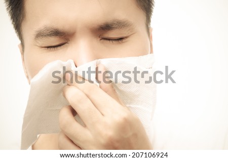 Flu cold & allergy symptom. Closeup of sick asian man with fever sneezing in tissue,  Sepia film processed