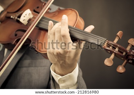 Asian male Musician plays Violin on Dark Background / sepia processed