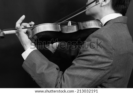 Asian male Musician plays Violin on Dark Background / B&W old film processed for vintage style photo
