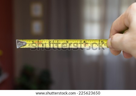 Hand holding measurement tape in the room for home decoration concept