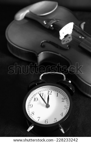 Low key image of alarm clock & old aged classical violin on black fabric , B&W processed  /  \