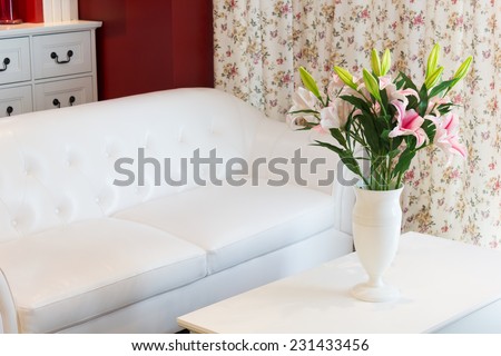 flowers in white vase on table,white leather sofa armchair & flowers pattern curtain, cozy living room