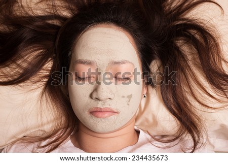 sleeping woman in clay mud facial mask on face on bed at night , Girl taking care of dry complexion. Beauty treatment