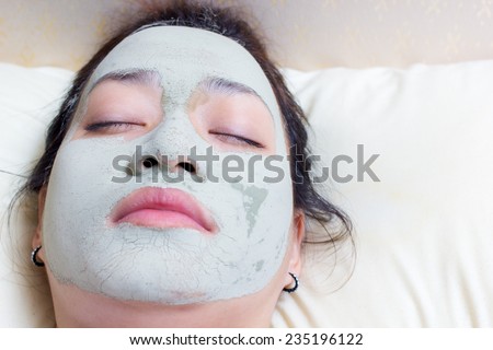sleeping woman in clay mud facial mask on face on bed , Girl taking care of dry complexion. Beauty treatment