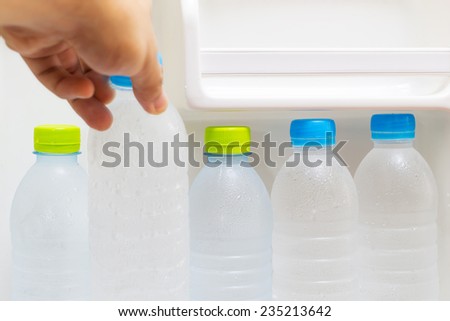 hand picks pure fresh cool bottles of water from refrigerator / health concept