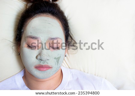 sleeping asian woman in clay mud facial mask on face on bed , Girl taking care of dry complexion. Beauty treatment