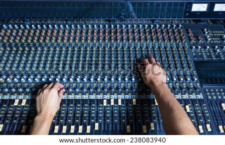 hands of sound engineer work on recording studio mixer, mixing board