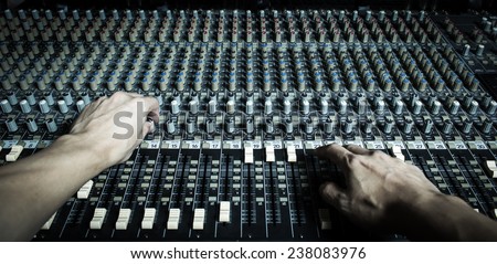 hands of sound engineer work on recording studio mixer, mixing board