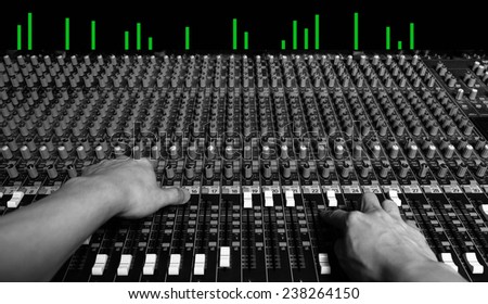 hands of sound engineer work on recording studio mixer, show green led level meter