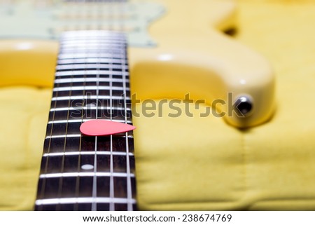 pink pick on yellow electric guitar fingerboard , shallow dept of filed & focus to pick