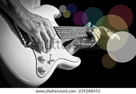 guitarist hand playing electric guitar isolated on black / black and white processed & colorful bokeh