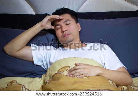 Asian man in bed suffering insomnia, headache and sleep disorder thinking about his problem