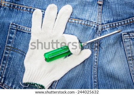 screwdriver on glove , on blue jeans / repair restore tools DIY concept