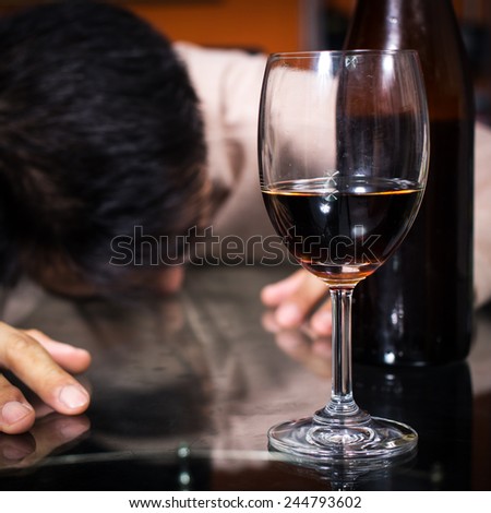 Drunk and lonely asian man & wine glass and wine, whiskey bottle / focus to glass