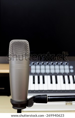 condenser microphone , music synthesizer keyboard & black monitor in recording studio / copy space on top for music concept