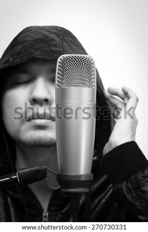 black and white emotion portrait of asian handsome male vocal, singer singing with condenser microphone in music recording studio