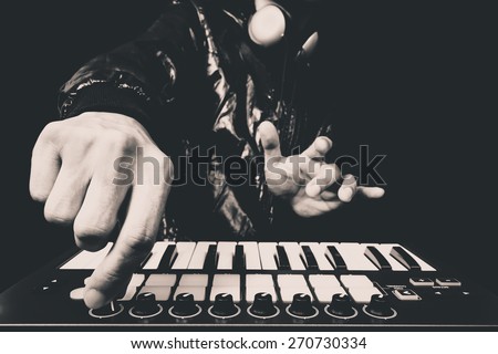professional musician or DJ hand on studio keyboard synthesizer, B&W isolated on black for dance , groove, remix, underground music background concept