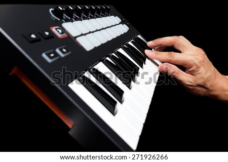 professional musician hand playing on studio keyboard synthesizer, focus to finger & isolated on black for dance , groove, remix, dubstep music background concept